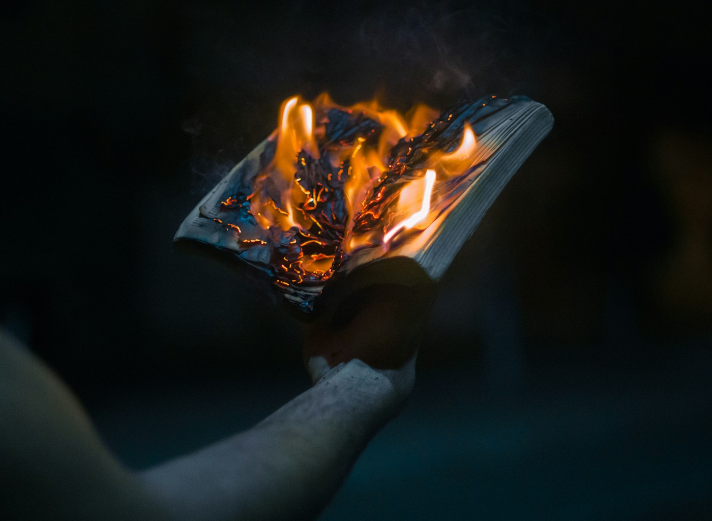 Hands holding burning paper at night — symbolic release and transformation